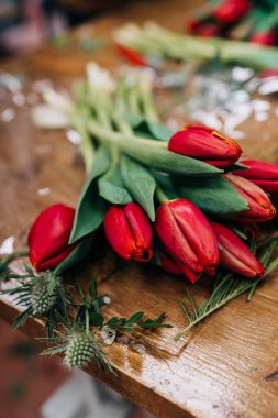 Adam çiçekçi kırmızı lale çiçek buketi ahşap masaya sağlar.