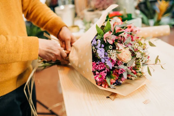 Man florist makes flowers bouquet  and wrapping in pack paper