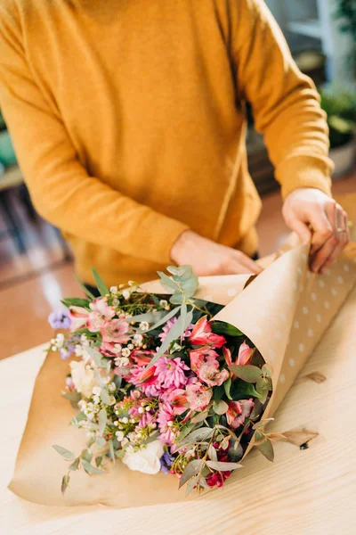 Man florist makes flowers bouquet  and wrapping in pack paper