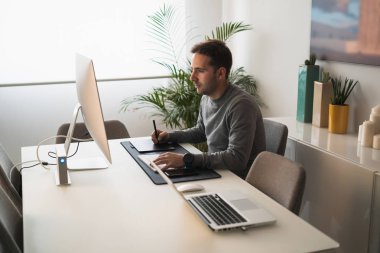 Evden çalışan serbest çalışan ve bilgisayar ve tablet kullanan bir adam.