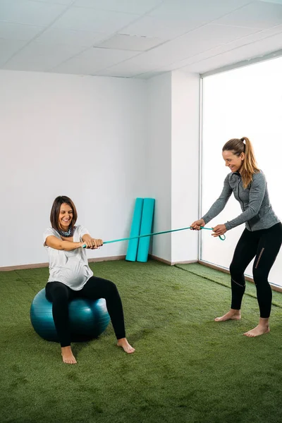 Pregnant woman doing fitness ball and pilates exercise with coac