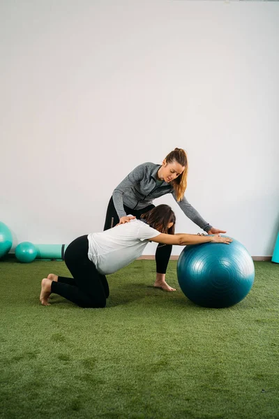 Pregnant woman doing fitness ball and pilates exercise with coac