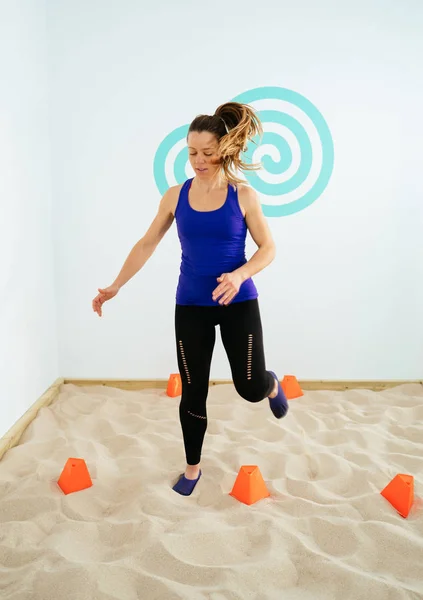 Young woman training on silica sand in a gym to recover the feet