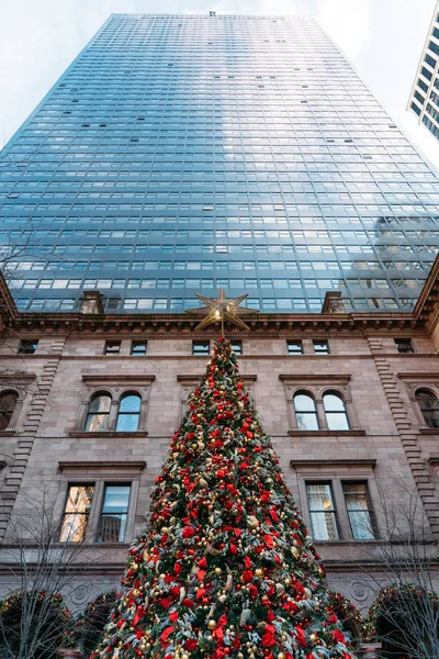 Un bellissimo albero di Natale decorato con molte palle rosse e gialle con grandi grattacieli sullo sfondo — Foto Stock