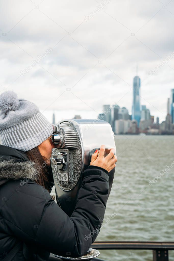 Beautiful woman looking through a telescope at New York City on 