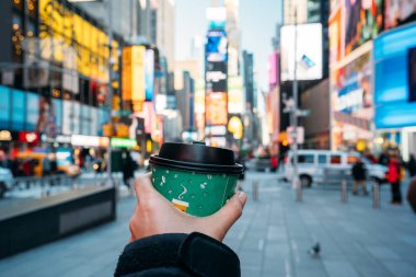 Arka planda New York City ile yeşil bir kahve bardağı tutan bir el detay - Bulanık renklerle güzel şehir
