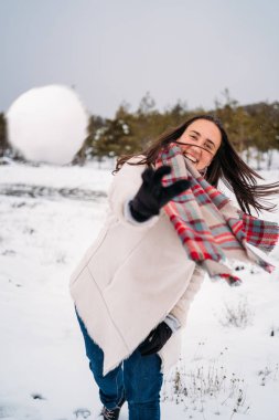 Güzel ve gülümseyen kadın bir ceket giymiş, kameraya kartopu atma - Tatil konsepti