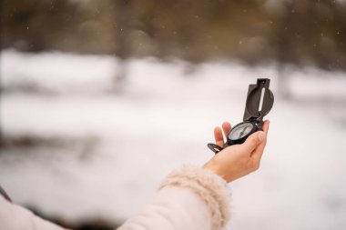 Karlı bir ormanda pusula tutan bir kadın eli