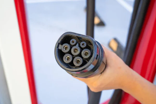 オスロ、ノルウェー - 2019年8月20日:電気自動車を充電するためのコネクタを保持する女性の手持ちプラグ。電源ケーブルを差し込んだ電気自動車の充電。エコエネルギーコンセプト — ストック写真