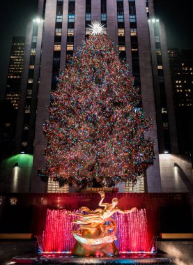 New York, Amerika Birleşik Devletleri, Aralık 25, 2108: Güzel bir Noel ağacı gece renkli ışıklar ve arka planda gökdelenler ile dekore - Dikey görüntü