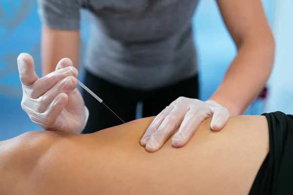 Photo detail of hands covered by medical gloves, inserting a small needle into a patient's leg. Relaxation concept. Close-up