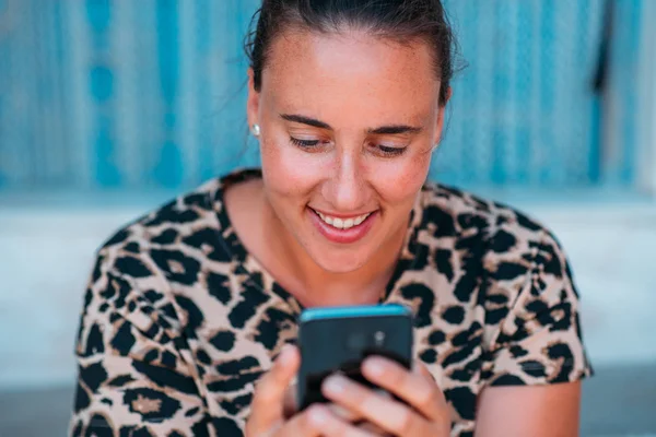 Close up de uma mulher feliz sorrindo usando um smartphone fora . — Fotografia de Stock