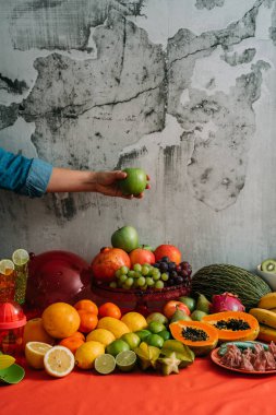 Kadın elleri taze organik meyve ve sebze büyük bir çeşitlilik ile bir masadan yeşil elma alarak. Detoks diyeti ve sağlıklı organik gıda kavramı.