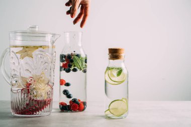 Kadın eli beyaz izole detoks suyu infüzyon yaban mersini ve ahududu ekleyerek. Sağlık ve detoksifikasyon kavramı.