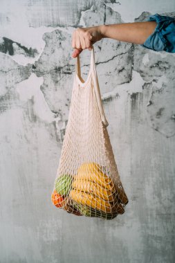 Yeniden kullanılabilir alışveriş çantasında organik taze meyveler tutan genç bir kadının yakın. String Eco Bag Alışveriş konsepti.