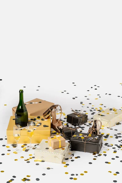Christmas background with gift boxes, confetti, bottle and glasses of champagne and party shoes. Preparation for holidays and parties. Top view with copy space. — Stock Photo, Image