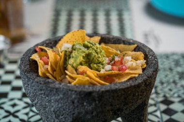 Biftek, guacamole, erimiş peynir, biber ve kişniş yapraklarıyla süslenmiş sarı mısır cipsi. Geleneksel Meksika havanı..