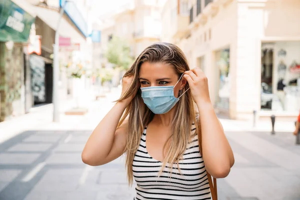 Donna in maschera in città utilizzando il suo cellulare durante la pandemia di coronavirus — Foto Stock