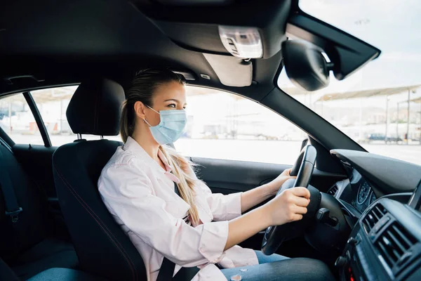 Vrouw met gezichtsmasker rijden haar auto tijdens coronavirus pandemie — Stockfoto