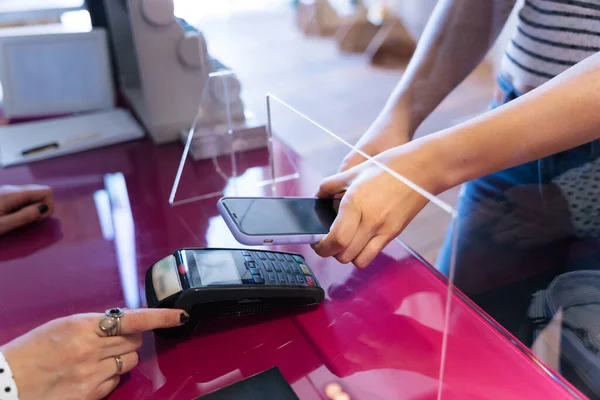 Woman paying with her smartphone in the coronavirus pandemic