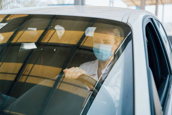 Vrouw met gezichtsmasker rijden haar auto tijdens coronavirus pandemie — Stockfoto