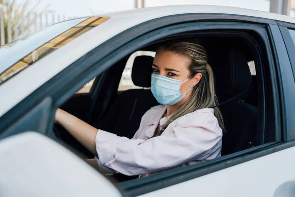 Vrouw met gezichtsmasker rijden haar auto tijdens coronavirus pandemie — Stockfoto