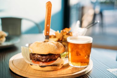 Lezzetli hamburgerler, patates kızartmaları ve ahşap kalaslarda servis edilen sos.