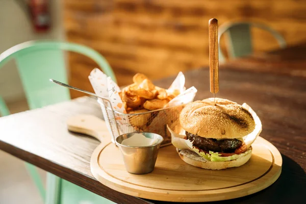 Delicious meet burger, fries and sauce served on wooden planks