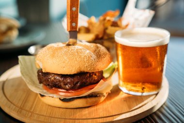 Lezzetli hamburgerler, patates kızartmaları ve ahşap kalaslarda servis edilen sos.