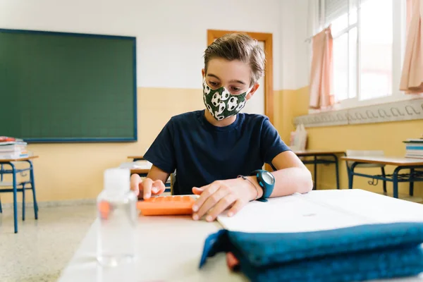 Een jongen die op haar stoel zat in de klas met een masker op. tijdens een hevige pandemie — Stockfoto