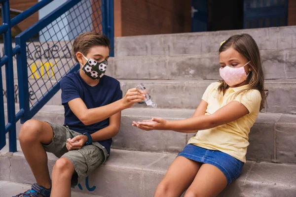 Los niños se ponen gel desinfectante en las manos en el aula de la escuela. Covid.. —  Fotos de Stock