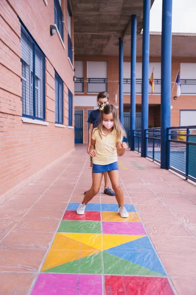 Back to school. Children running and jumping in the schoolyard with face mask — Stock Photo, Image