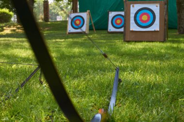 Okçuluk kavramı, hedefler ve bir yay ön planda yeşil çimen genelinde düşük açılı manzaralı
