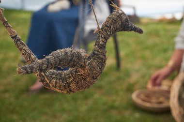 El yapımı uçan kuş yapılan kurutulmuş ot ve saman arka planda geliştirmelerde geleneksel giysiler içinde oturan bayanlar ile dize ile bağlı