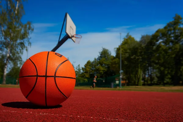 Basketbol ağaçlar ve mavi bulutlu gökyüzü karşı açık basketbol mahkeme katta. Ücretsiz kopya alanı.