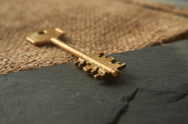Acces, özellik veya güvenlik sembolü olarak vintage bir altın anahtar kavramsal close-up. Seçici odak ve ücretsiz kopya alanı.