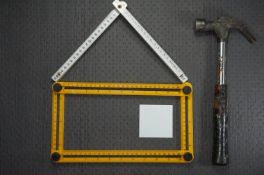 Kavramsal İnşaat ve tadilat natürmort sarı ve beyaz yöneticiler tarafından kurulan bir ev daire yatıyordu tasarımı ile çekiç ve bir siyah boş yapışkan notlar delikli arka plan