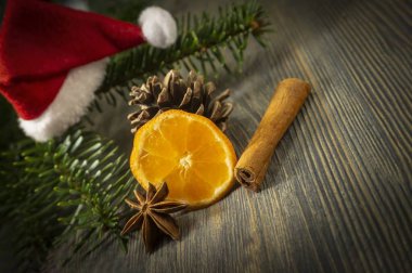 Yanında kopya alanı ahşap masa yüzey zemin üzerine oturan çam dal ve kırmızı Noel Baba şapkası, portakal, tarçın ve badian Yıldız anason parçası. Noel arka plan, mulled şarap tarifi kavramı