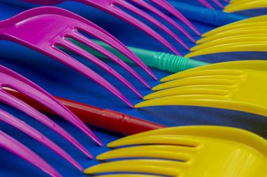 Sarı ve pembe çatal plastik çatal ve çubuk mavi zemin üzerine düzenlenmiş. Renk trendleri ve plastik atık sorunu kavramı