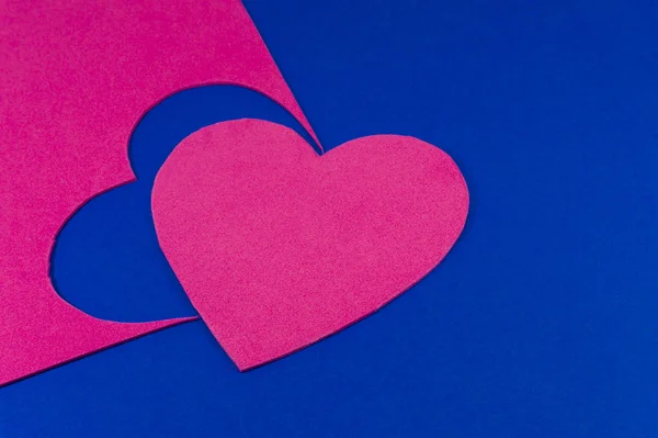 Hearts cut out of bright pink color foam sheets viewed in full frame background. Bright pink heart on blue sheet viewed from above. Love and relationship Valentines Day and color trends concept
