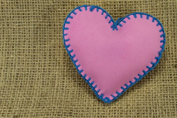 Valentine Day template, one handmade pink foam sheet stitched toy heart on jute canvas, close up, high angle view. Love, relationship, Valentines Day, lesbian love concept