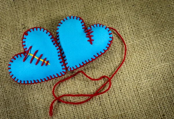 Valentine Day template, two handmade blue foam sheet stitched toy hearts on jute canvas, close up, high angle view. Love, relationship, Valentines Day, broken heart and gay love concept