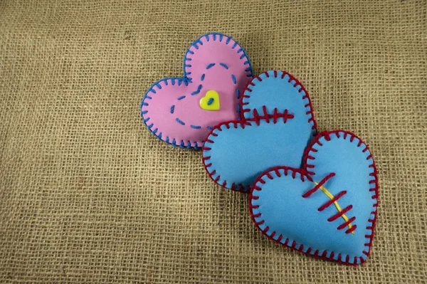 Valentine Day template, handmade pink and blue foam sheet stitched toy hearts on jute canvas, close up, high angle view. Love, relationship, Valentines Day, broken heart concept