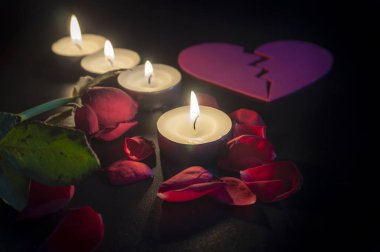 Dört çay mumlar ve odak sığ derinliği ile karanlıkta kırmızı gül yaprakları