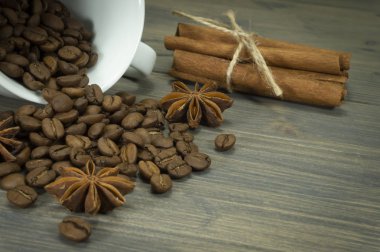 Kavrulmuş kahve Kupası, yıldız anason baharat görünümü kadar yakın bir rustik ahşap tablo ile tarçın dökülmeye fasulye