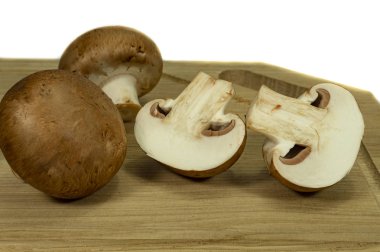 Beyaz bir arka plan üzerinde izole bir ahşap kesme tahtası üzerinde taze bütün ve yarıya brown (Bebek Bella) Mantar