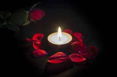 Çay mum, kırmızı gül ve gül yaprakları üzerinde siyah