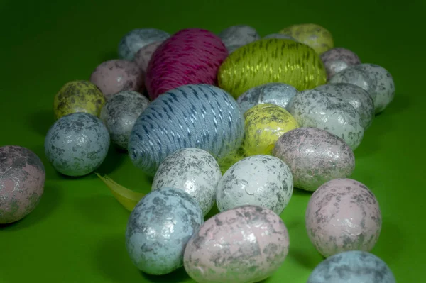 Handmade Easter eggs and yellow feathers on green — Stock Photo, Image