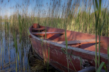 Kırsal bir iskeleye demirlenmiş ahşap kırmızı kayık.