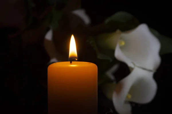 Nahaufnahme orangefarbener Kerzenflamme und Lilienblüten — Stockfoto